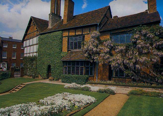 An impressive old English house, covered in vines and shrubs that have been well looked after. Pictured on a warm summers day.